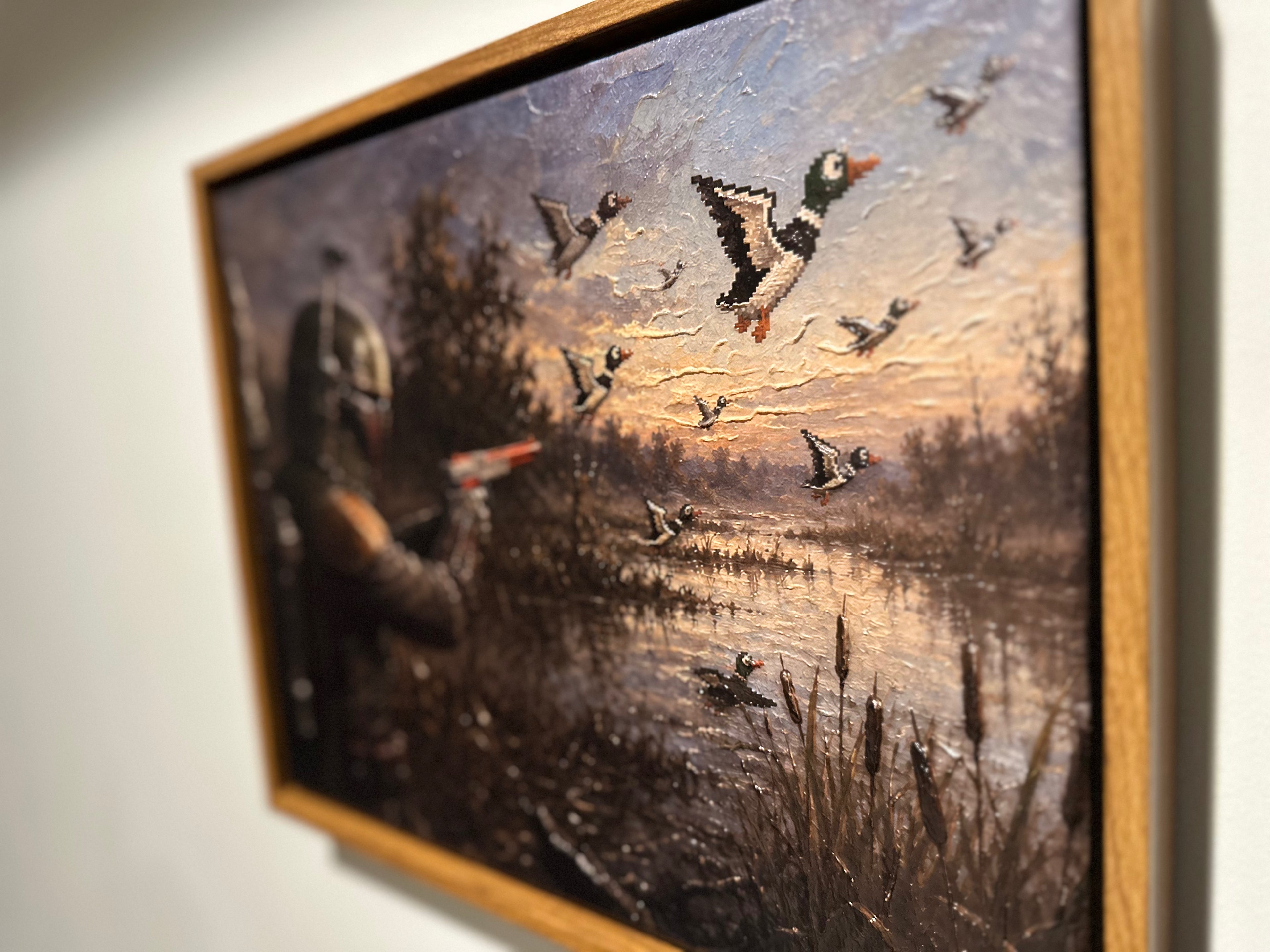 A framed painting depicting a Star Wars Mandalorian in armor aiming a blaster at flying mallards by a marsh, shown hanging on a light wall.